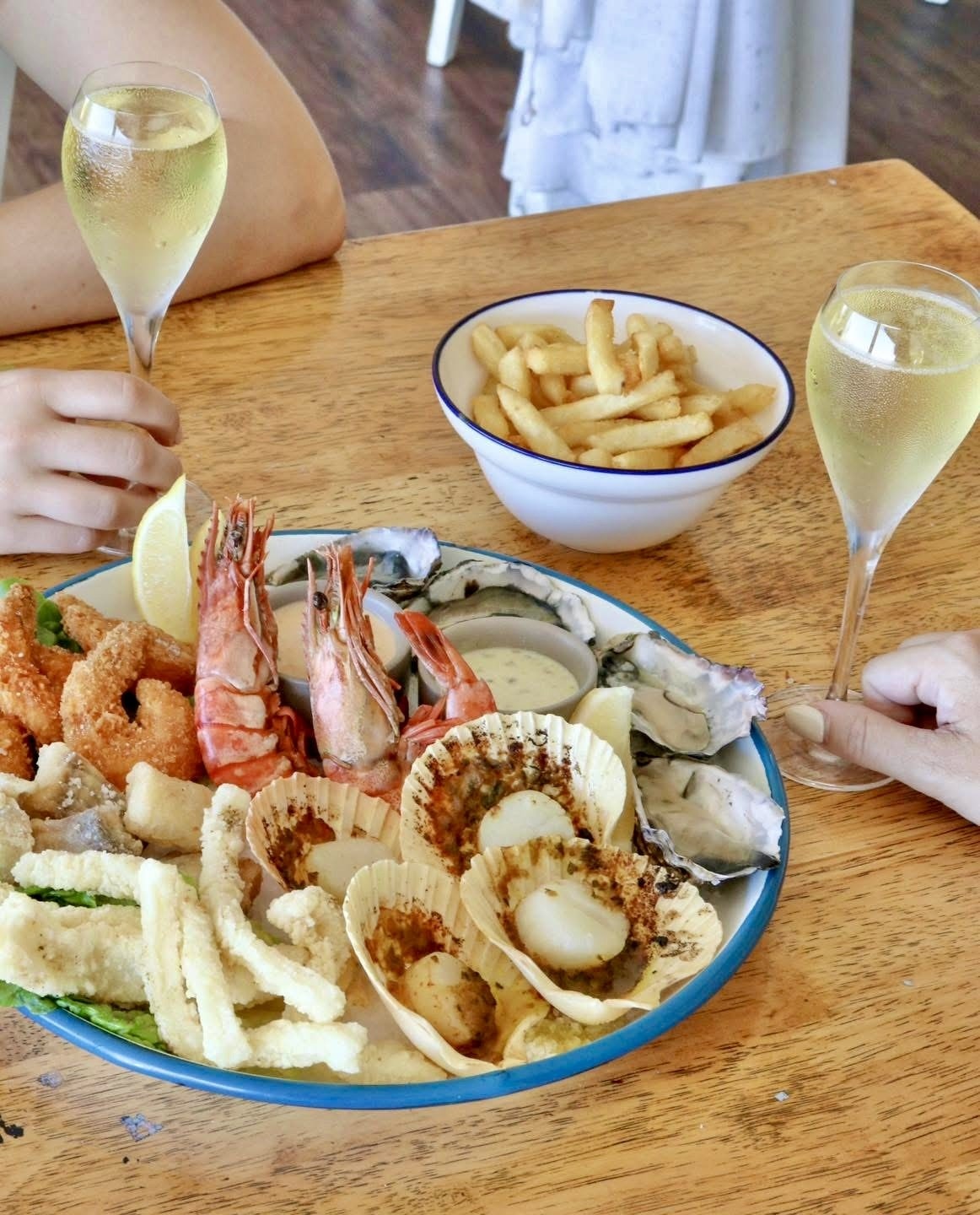Shared seafood platter with prawns, scallops, calamari and champagne