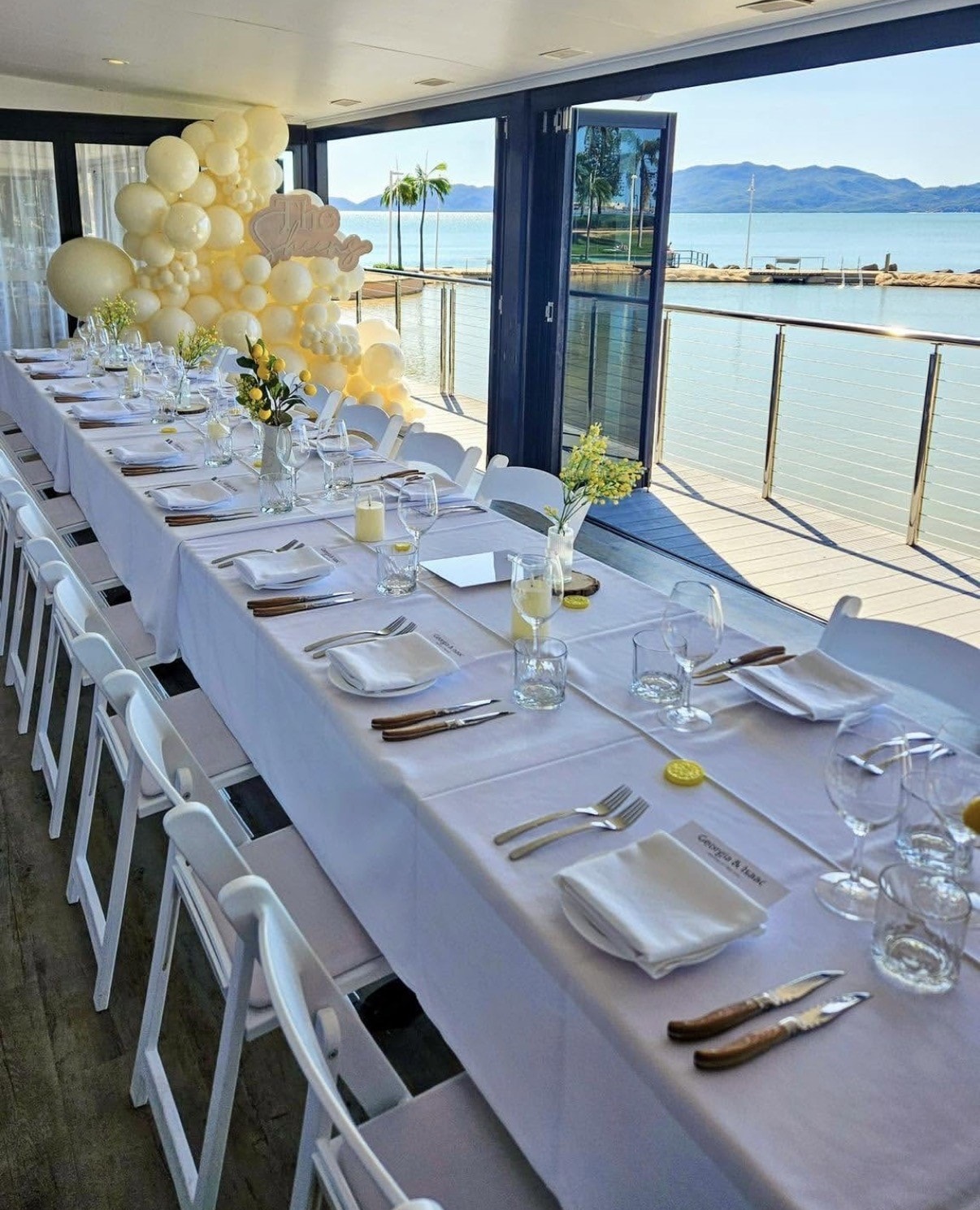 Waterfront banquet with balloon arch and long table setting